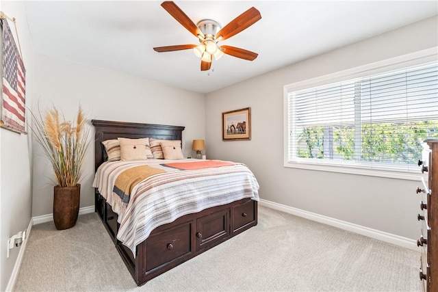 bedroom featuring light carpet, a ceiling fan, and baseboards