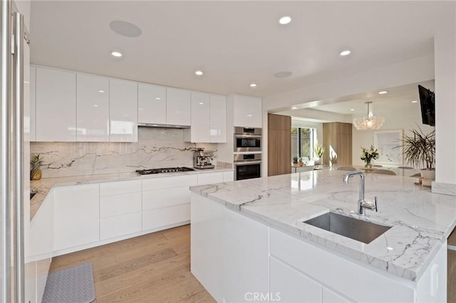 kitchen with sink, light stone countertops, white cabinets, and appliances with stainless steel finishes