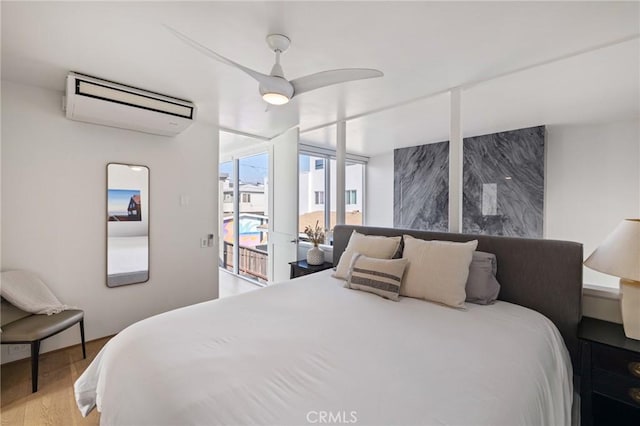 bedroom with ceiling fan, access to outside, a wall mounted AC, and light hardwood / wood-style floors