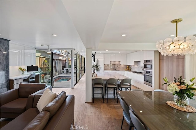 living room featuring sink, ceiling fan with notable chandelier, and light hardwood / wood-style floors