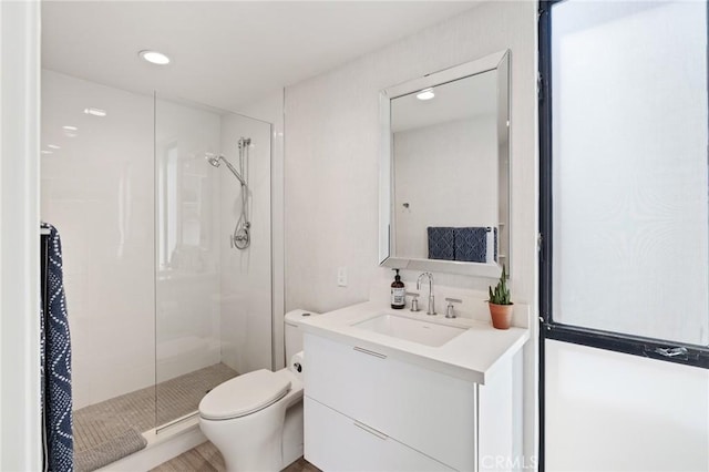 bathroom with vanity, toilet, and a shower with door