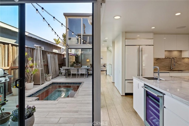 back of property with a patio, a swimming pool, sink, and wine cooler