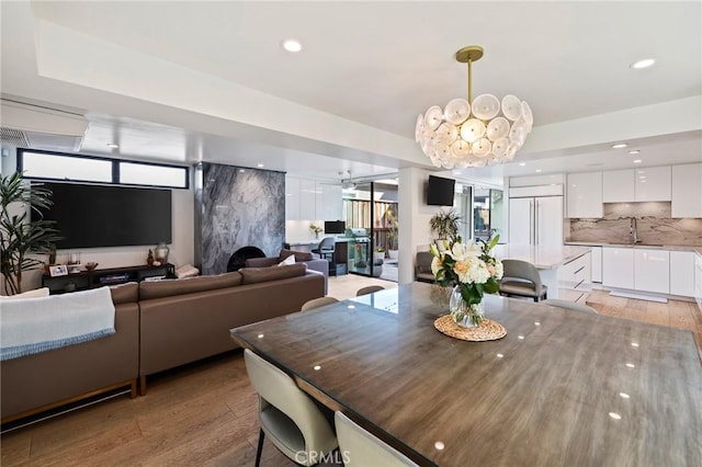 dining space featuring sink, ceiling fan with notable chandelier, and light hardwood / wood-style flooring