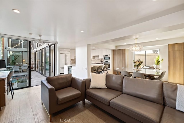 living room featuring a wealth of natural light, a notable chandelier, and light hardwood / wood-style flooring