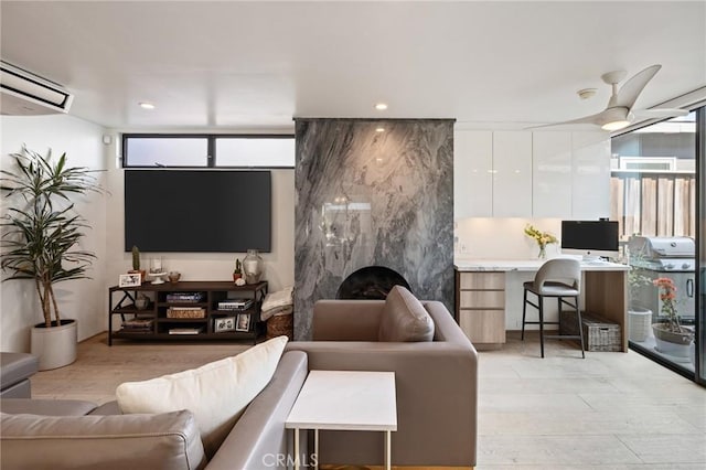 living room featuring ceiling fan, a fireplace, built in desk, and an AC wall unit