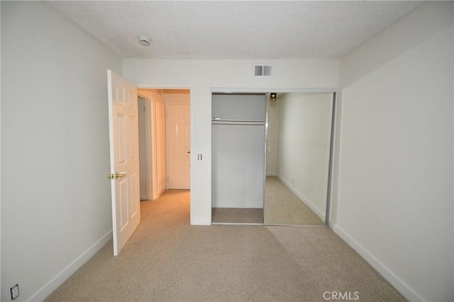 unfurnished bedroom with light colored carpet and a closet