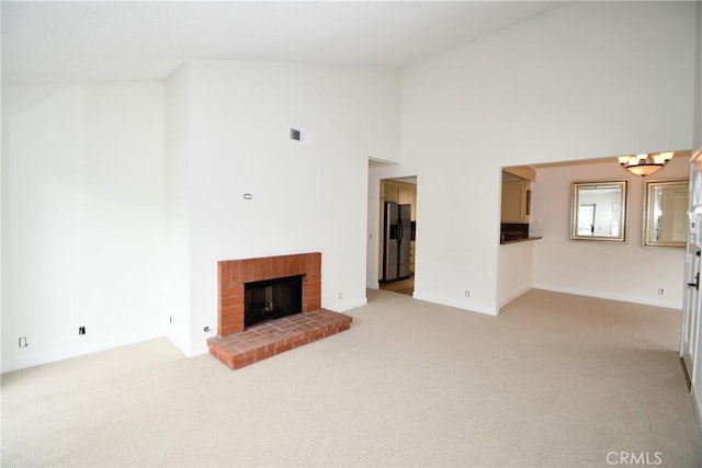 unfurnished living room featuring high vaulted ceiling, light carpet, and a fireplace