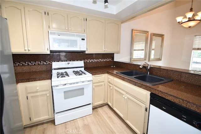 kitchen featuring sink, light hardwood / wood-style flooring, white appliances, and cream cabinetry