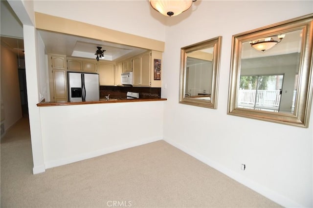 kitchen featuring a raised ceiling, stainless steel refrigerator with ice dispenser, light carpet, and range