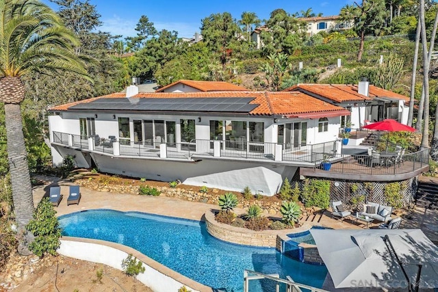 rear view of property with a balcony, a patio area, and solar panels