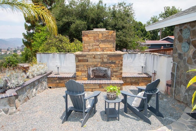 view of patio featuring a mountain view and an outdoor stone fireplace