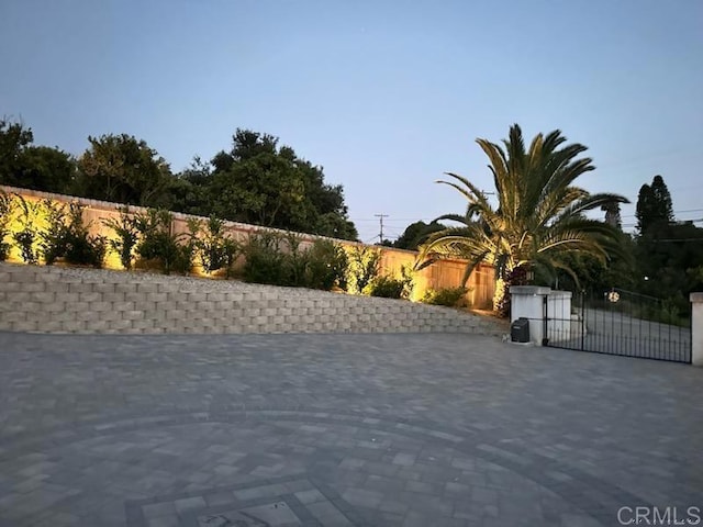 view of road with decorative driveway and a gate