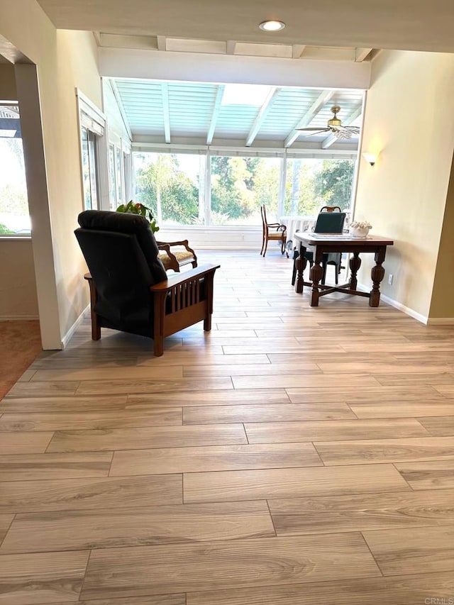 sunroom featuring beamed ceiling and a ceiling fan