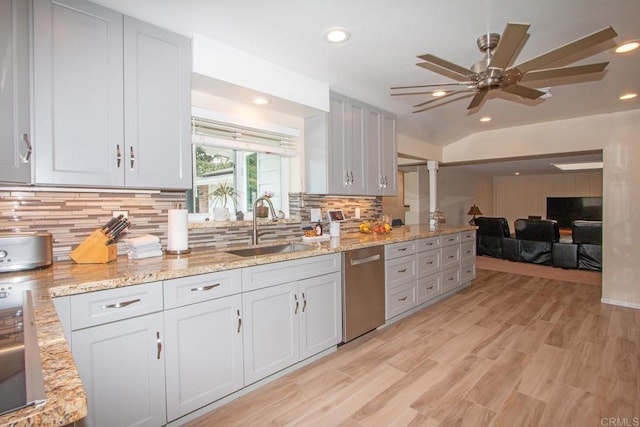 kitchen with open floor plan, decorative backsplash, stainless steel dishwasher, light wood-style floors, and a sink