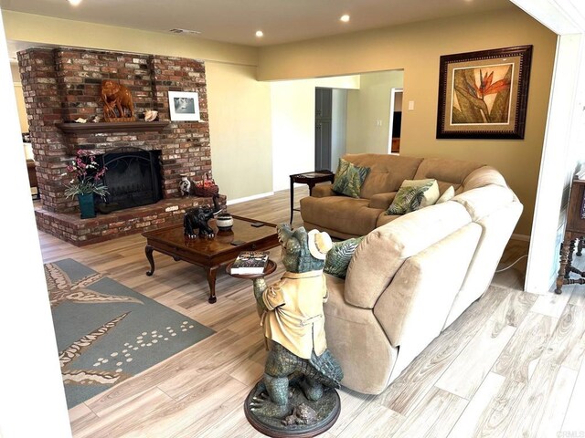 living area featuring recessed lighting, baseboards, a brick fireplace, and wood finished floors