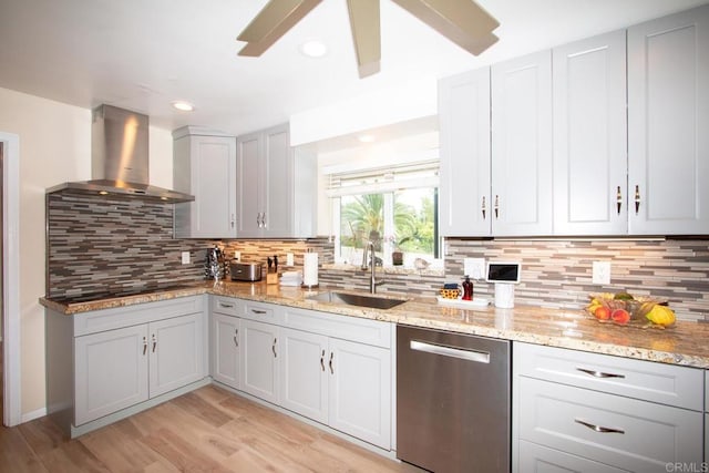 kitchen with a sink, light wood-style floors, wall chimney exhaust hood, black electric stovetop, and dishwasher