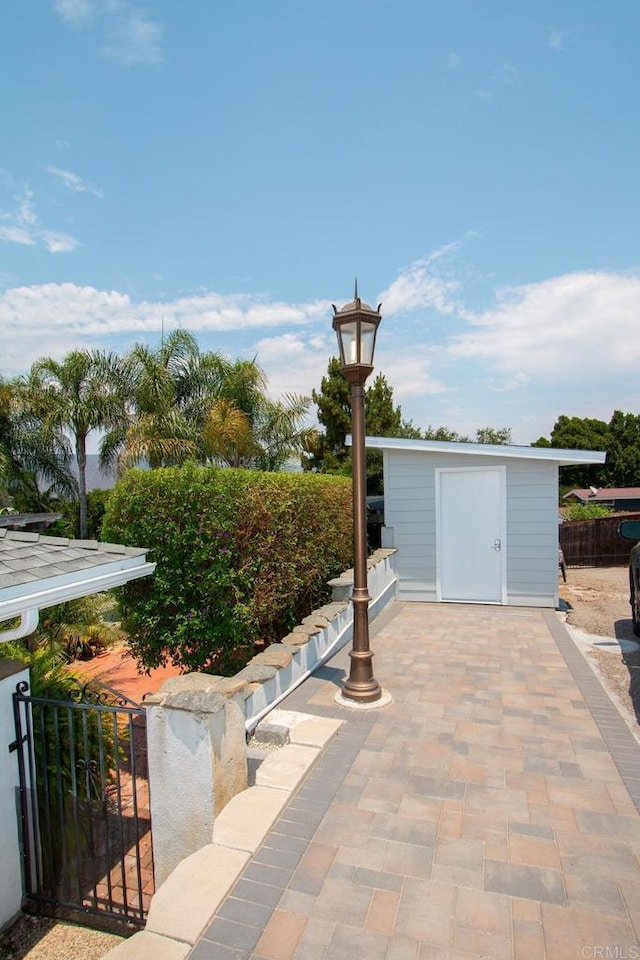 view of patio featuring a storage unit, an outdoor structure, and fence