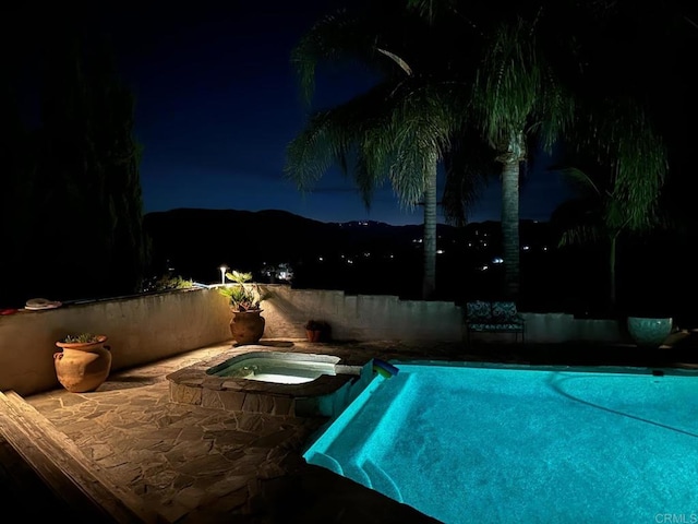 pool at twilight with an in ground hot tub and a fenced in pool