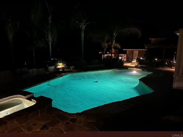 pool at twilight featuring a patio area and a pool with connected hot tub