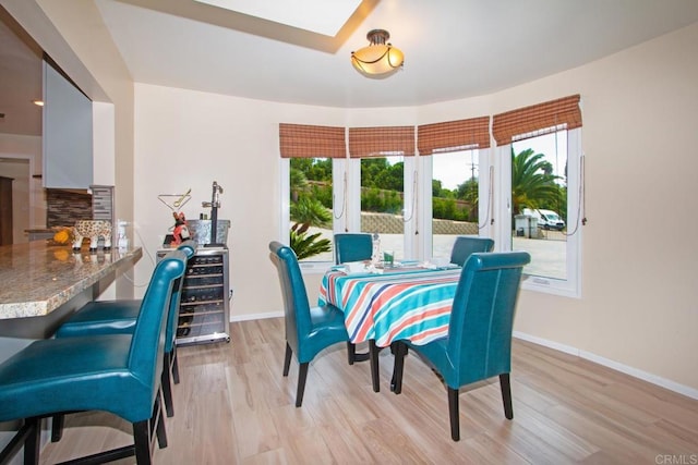 dining area featuring baseboards, light wood-style floors, and a skylight