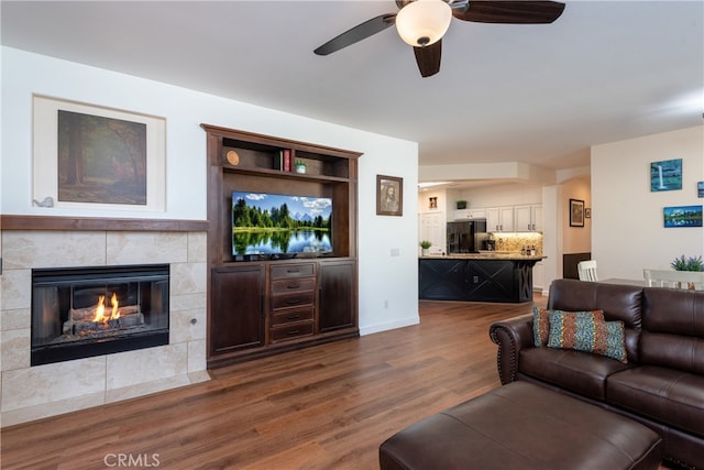 living room with ceiling fan, a fireplace, and dark hardwood / wood-style floors