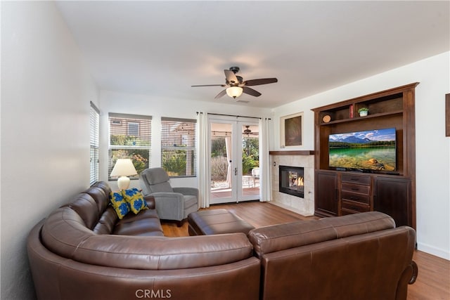 living room with a tiled fireplace, hardwood / wood-style floors, french doors, and ceiling fan