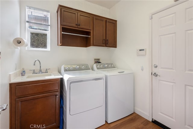 laundry area with separate washer and dryer, sink, wood-type flooring, and cabinets