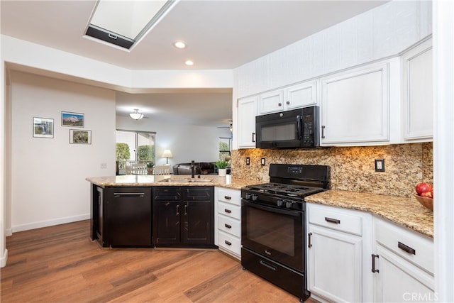 kitchen featuring tasteful backsplash, sink, white cabinets, light hardwood / wood-style floors, and black appliances