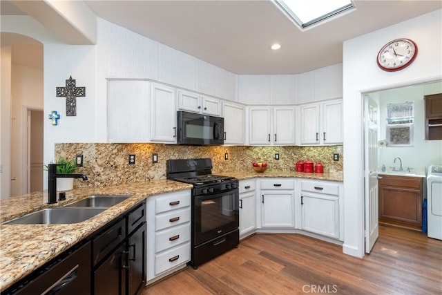 kitchen with white cabinetry, backsplash, sink, and black appliances