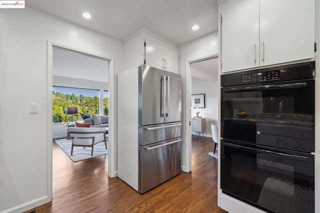 kitchen featuring double oven, dark wood-type flooring, stainless steel refrigerator, and white cabinets