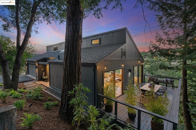 back house at dusk featuring a garage