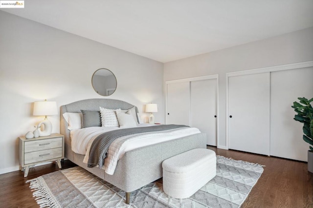 bedroom with dark hardwood / wood-style floors and multiple closets