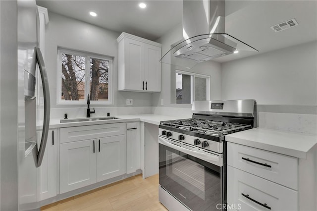 kitchen featuring sink, island range hood, light hardwood / wood-style flooring, stainless steel appliances, and white cabinets