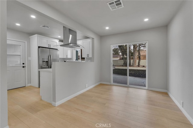 kitchen with white cabinetry, stainless steel fridge with ice dispenser, kitchen peninsula, island exhaust hood, and light hardwood / wood-style floors