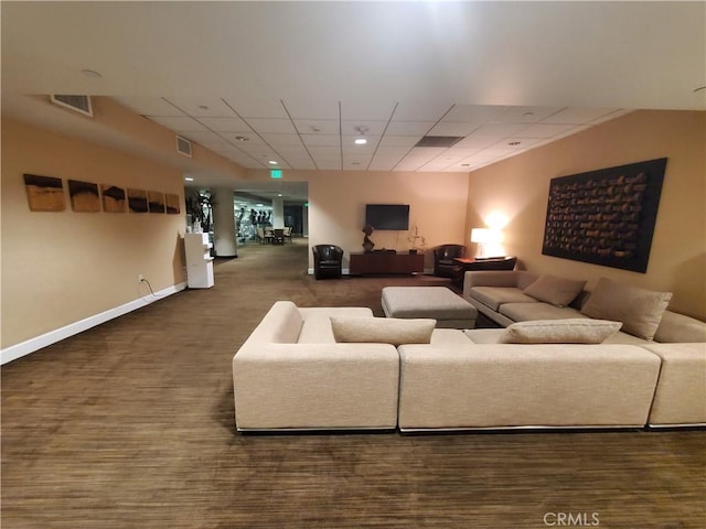 living room with a drop ceiling and carpet