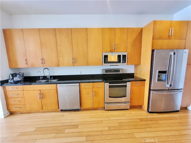 kitchen with appliances with stainless steel finishes, light hardwood / wood-style floors, and sink