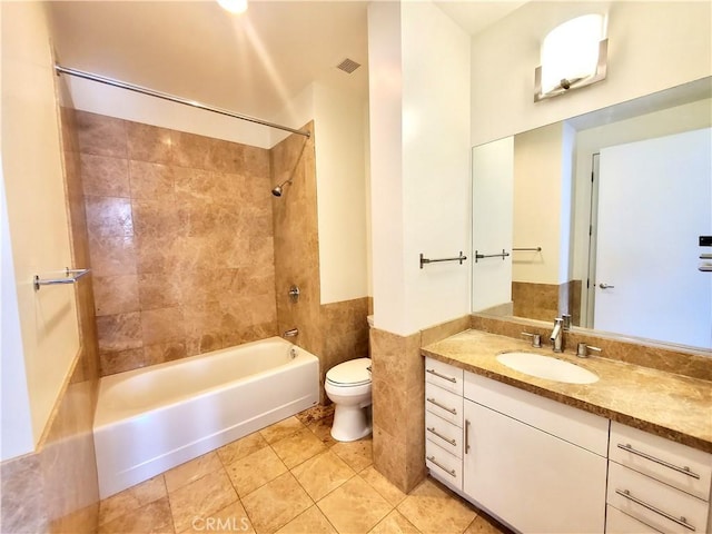 full bathroom with tile walls, tiled shower / bath combo, vanity, tile patterned flooring, and toilet