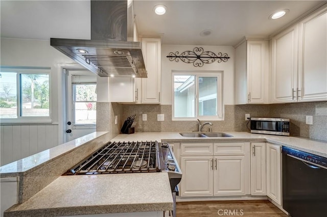 kitchen featuring island range hood, white cabinetry, sink, kitchen peninsula, and stainless steel appliances