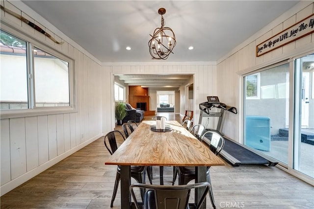 dining room with a fireplace, a chandelier, and light hardwood / wood-style flooring