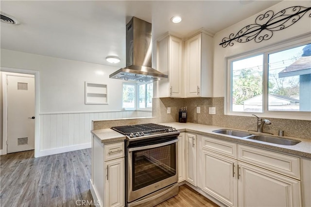 kitchen featuring sink, tasteful backsplash, ventilation hood, light hardwood / wood-style floors, and stainless steel range with gas cooktop