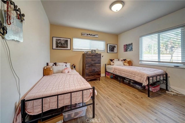 bedroom with multiple windows and light wood-type flooring