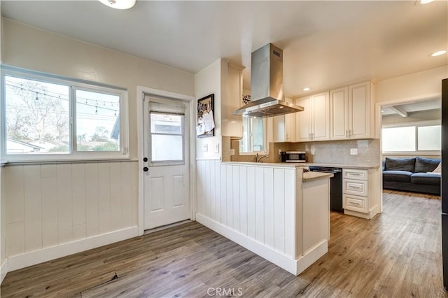 kitchen with light hardwood / wood-style floors, kitchen peninsula, black dishwasher, and island exhaust hood