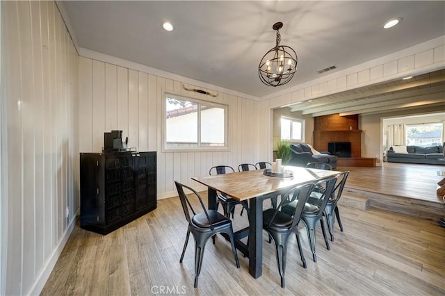 dining room featuring a brick fireplace, light hardwood / wood-style flooring, and a wealth of natural light