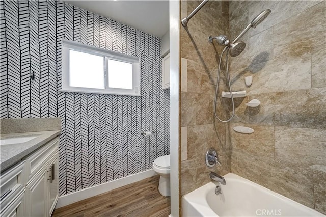 full bathroom featuring vanity, hardwood / wood-style floors, tiled shower / bath combo, and toilet