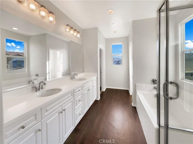 bathroom featuring wood-type flooring, a bath, vanity, and plenty of natural light