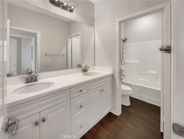 full bathroom with vanity, hardwood / wood-style floors, shower / washtub combination, and toilet