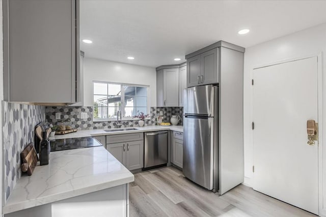 kitchen featuring appliances with stainless steel finishes, gray cabinets, light stone countertops, and sink