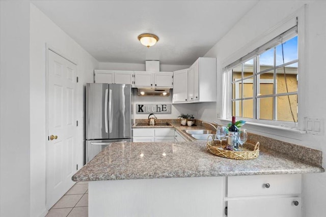 kitchen featuring light tile patterned flooring, sink, stainless steel refrigerator, light stone countertops, and white cabinets