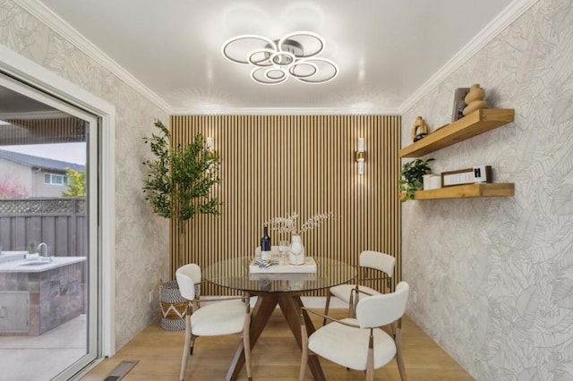 dining room with ornamental molding and light hardwood / wood-style flooring