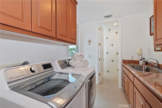 clothes washing area featuring cabinets, sink, and washing machine and dryer